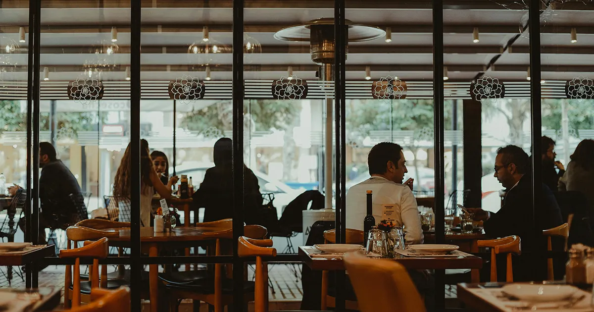 Clientes cenando en un restaurante mientras el negocio opera con buena gestión y liderazgo.