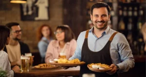 Dueño de restautaurante sonrie al ver su restaurante lleno de clientes, ofrece atención personalizada