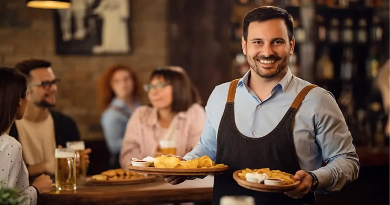 Dueño de restautaurante sonrie al ver su restaurante lleno de clientes, ofrece atención personalizada
