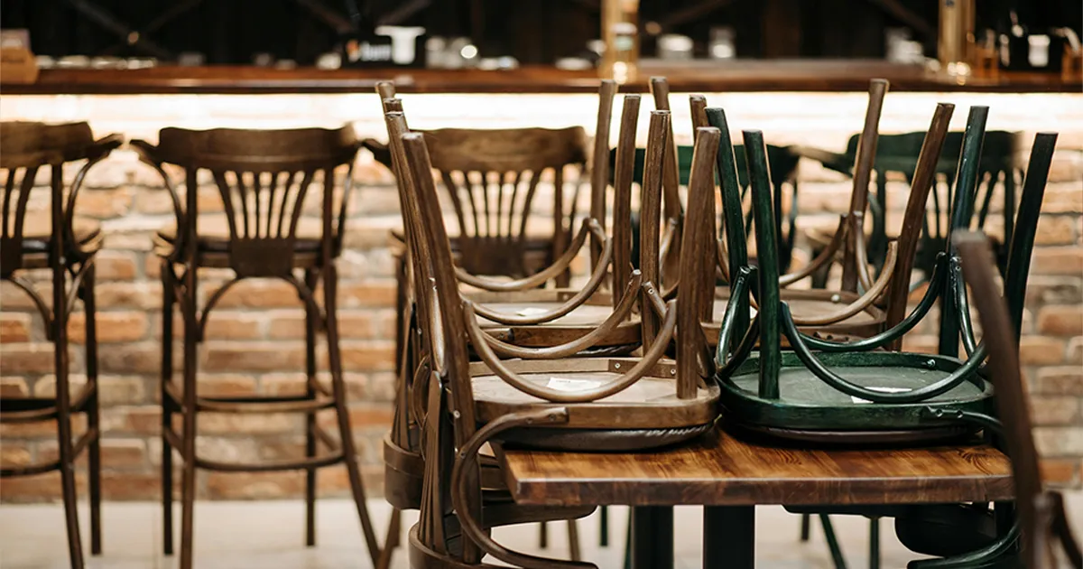 Interior de un restaurante vacío con las sillas sobre las mesas, representando una crisis en el negocio.