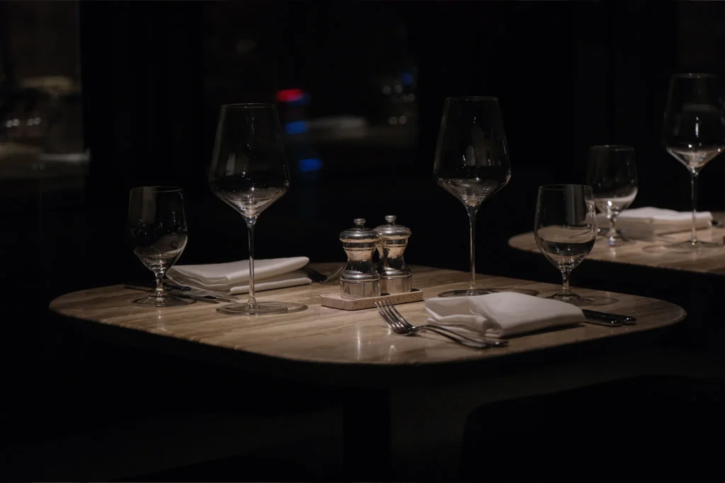 copas-mesa-luz-apagada-restaurante Mesa de restaurante vacía preparada para recibir clientes.